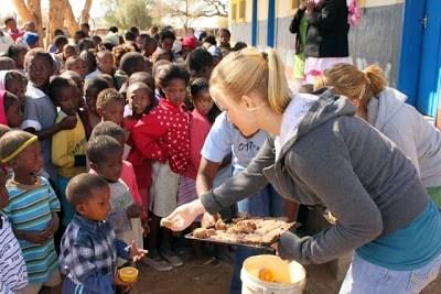 Sarah-Grace Prestidge offers food to a group of children