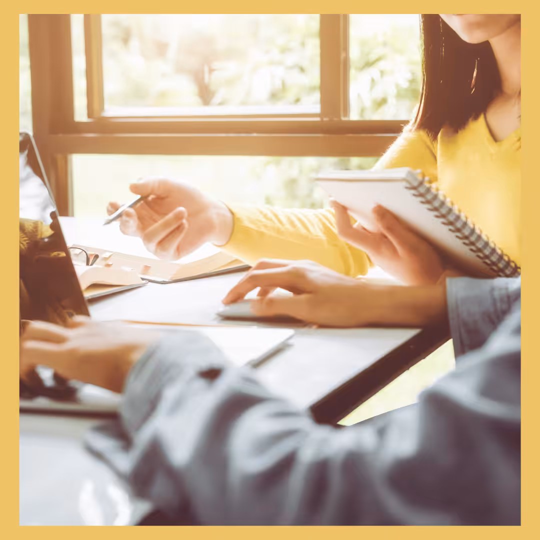 Two people working together on a problem using a computer. 