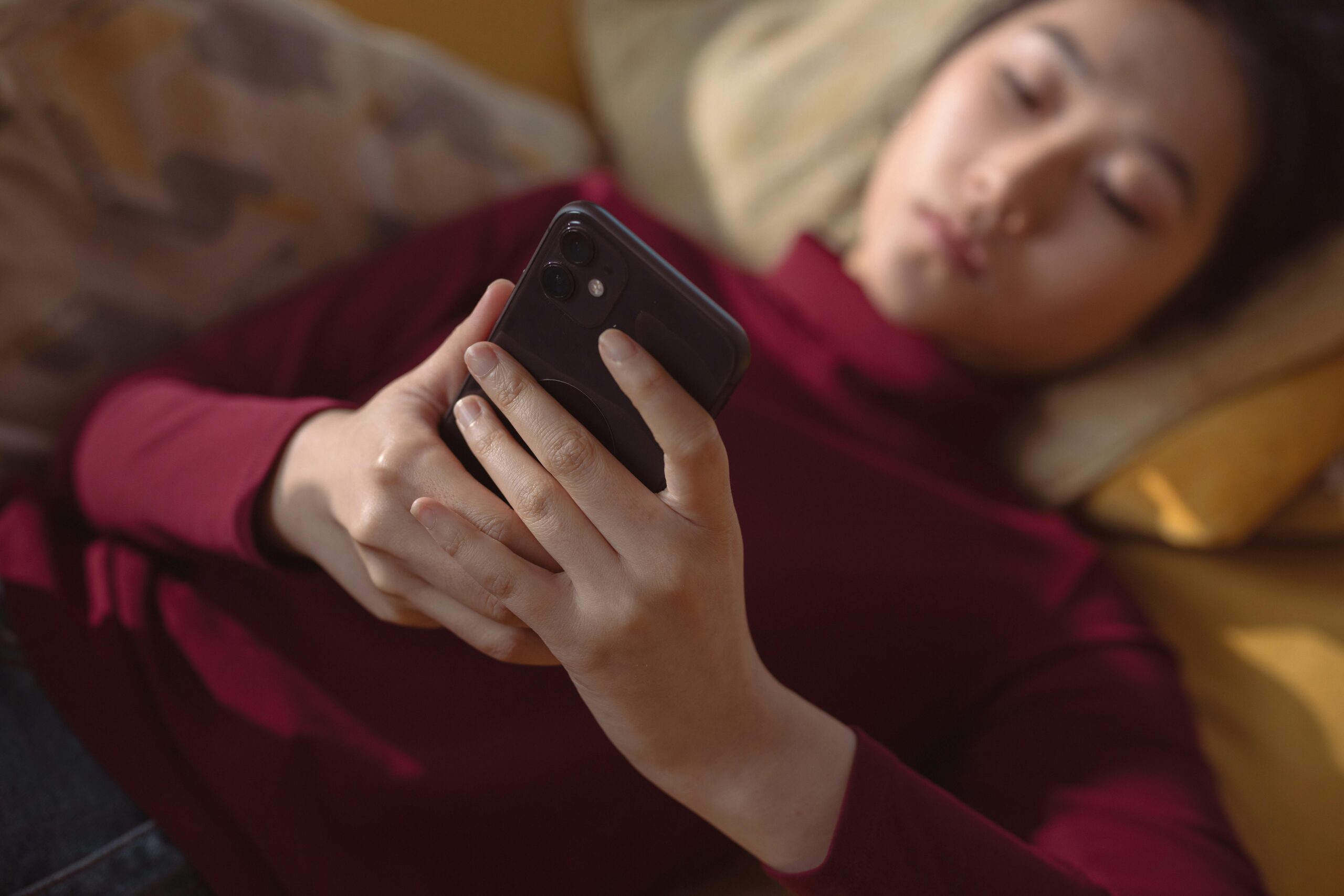 Grieving girl reading text message_lying down in red sweater
